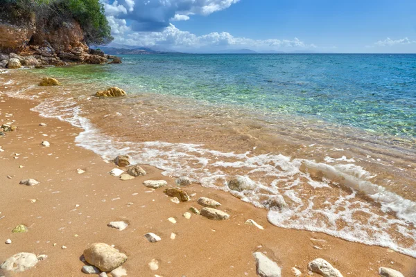 Vista para maré onda sobre seixos e rochas na areia — Fotografia de Stock