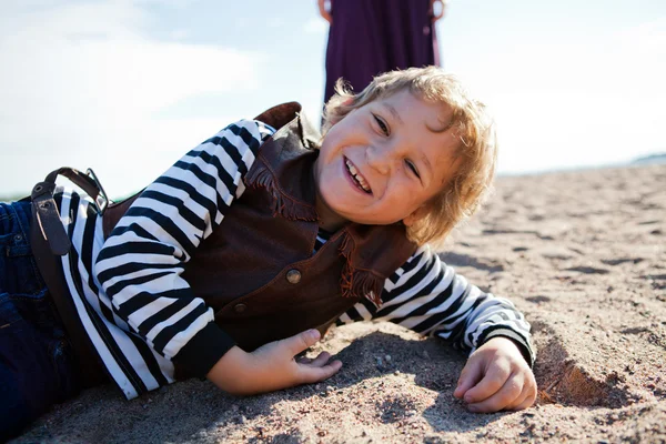 Uśmiechnięty chłopiec leżąc na plaży. — Zdjęcie stockowe