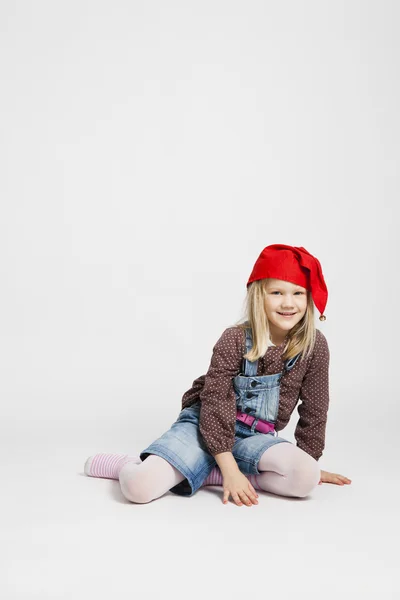 Leende flicka klädd jul hatt sitter — Stockfoto