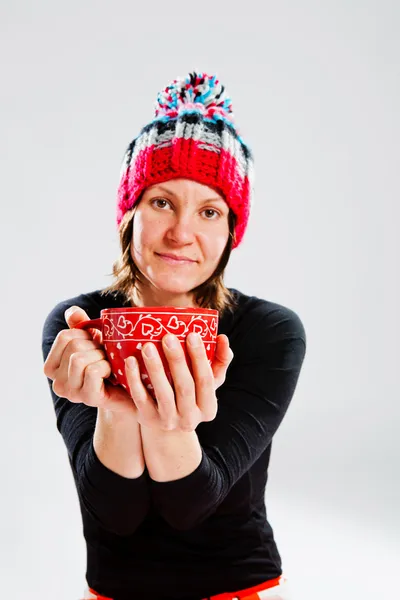 Smiling woman in knitted hat holding cup — Stock Photo, Image