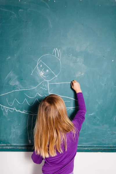 Jong meisje puttend uit schoolbord — Stockfoto