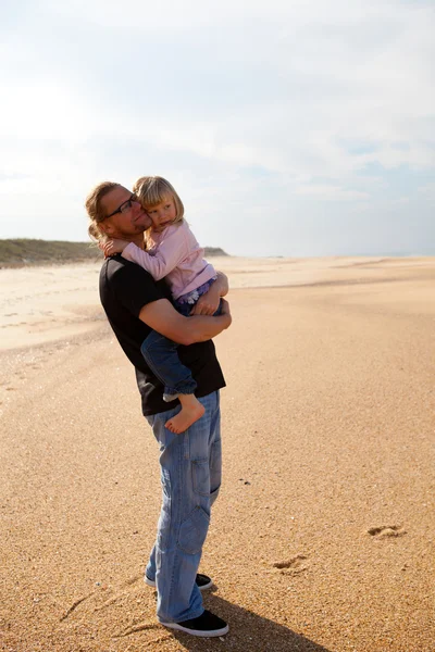 Padre sosteniendo a su hija en brazos en la playa — Foto de Stock