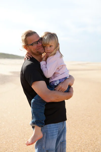 Otec dcera hospodářství v náručí na pláži — Stock fotografie