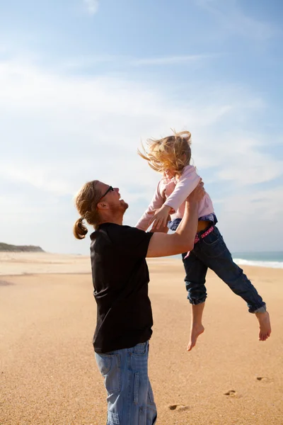 Vader dochter gooien in de lucht op het strand — Stockfoto