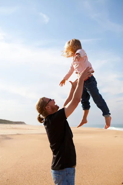 Otec házení dcera ve vzduchu na pláži — Stock fotografie