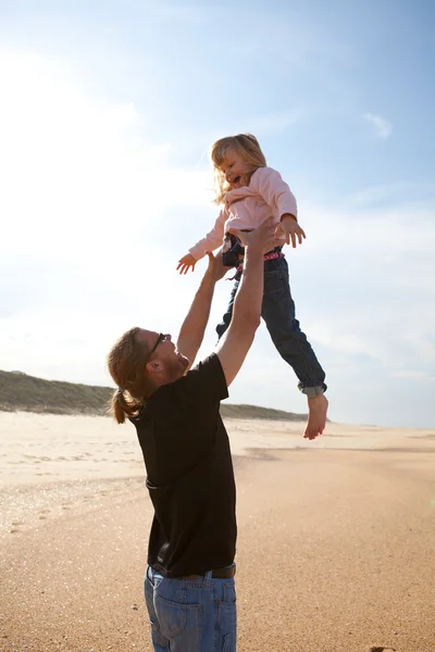 Vader dochter gooien in de lucht op het strand — Stockfoto