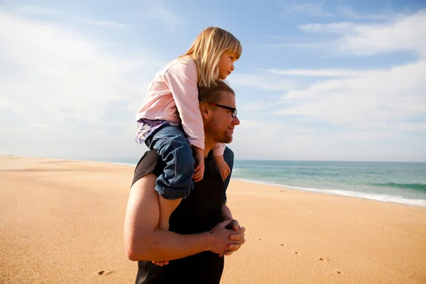 Father carrying daughter on shoulders at the beach — Stock Photo, Image