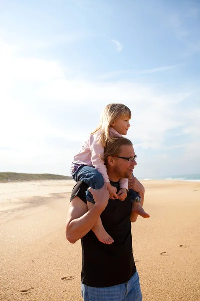 Father carrying daughter on shoulders at the beach — Stock Photo, Image