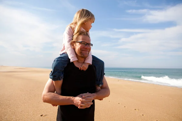 Father carrying daughter on shoulders at the beach — Stock Photo, Image