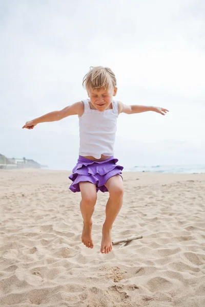 Young girl jumping in sand — Stock Photo, Image