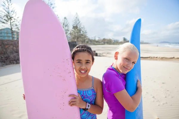 Dwa szczęśliwy dziewcząt gospodarstwa deski surfingowe na plaży — Zdjęcie stockowe