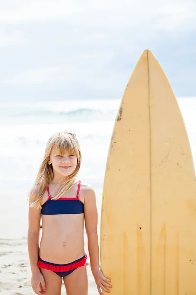 Sonriente joven de pie junto a la tabla de surf — Foto de Stock