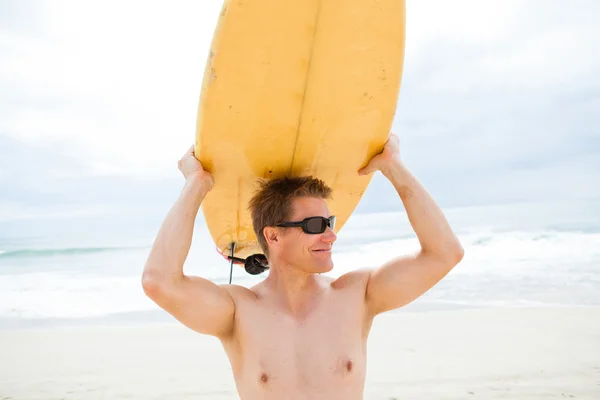 搁在头在海滩上的冲浪板的男人微笑着 — 图库照片