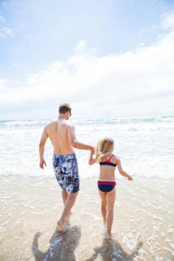 Baba ve genç kızı plajda su içine yürüyüş