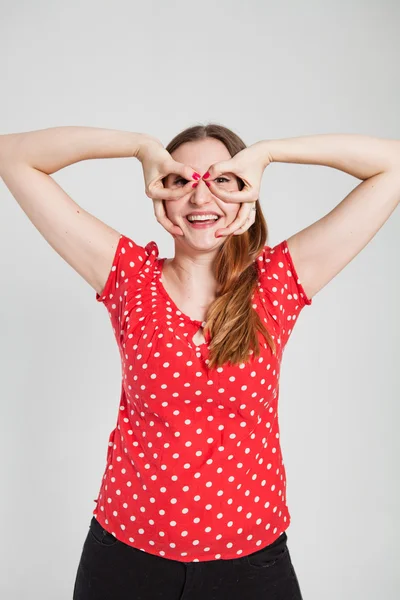 Mujer atractiva sonriente a través de gafas de dedo —  Fotos de Stock