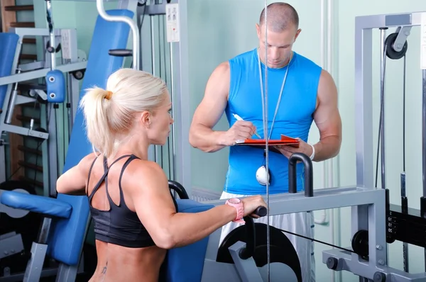 Mujer en ejercicio de gimnasio con entrenador de fitness personal — Foto de Stock