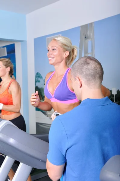 Duas mulheres no ginásio exercitando com personal fitness trainer — Fotografia de Stock