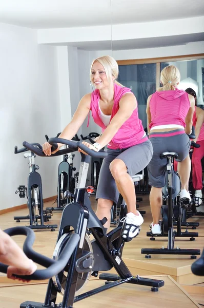 Vackra kvinnor gör övning i en spinning klass på gym — Stockfoto