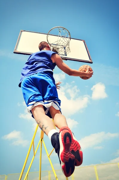 Jugador de baloncesto en acción volando alto y anotando — Foto de Stock