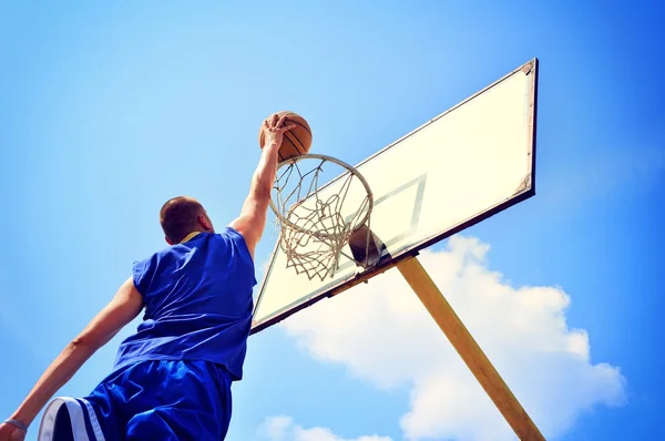 Jugador de baloncesto en acción volando alto y anotando — Foto de Stock