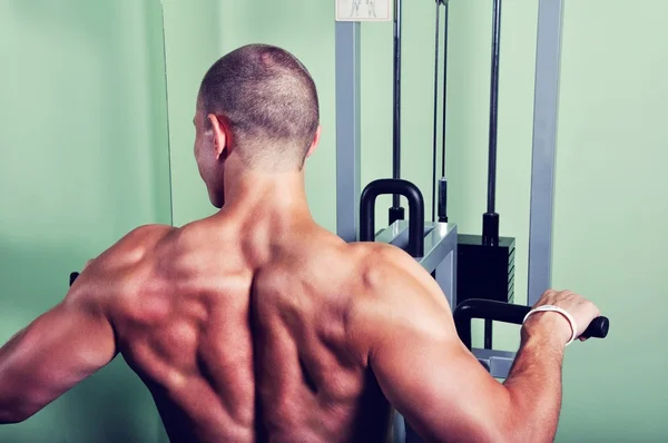 Hombre musculoso haciendo ejercicio en un gimnasio —  Fotos de Stock