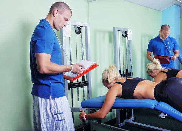 Mujer en el gimnasio haciendo ejercicio con entrenador de fitness personal — Foto de Stock