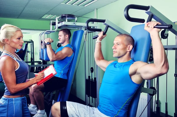 Female personal fitness trainer with two Athlete man in gym Royalty Free Stock Photos