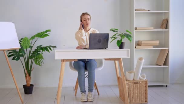 Junge kaukasische Frau telefoniert am Arbeitsplatz — Stockvideo