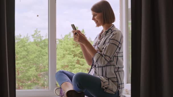 Kvinnliga meddelanden som håller mobilen hemma — Stockvideo