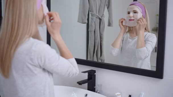 Alegre rubia hace procedimientos cosméticos en casa — Vídeos de Stock
