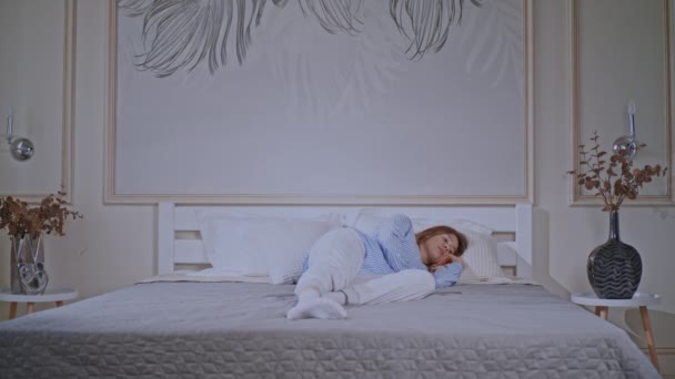 Mujer rubia acostada en la cama despierta — Vídeos de Stock