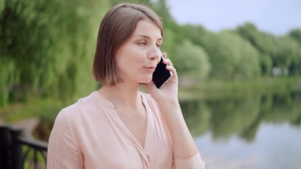 Молода жінка розмовляє по телефону на ходу — стокове відео