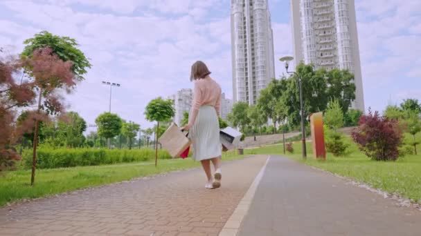 Joyful woman walks with varicoloured paper bags — Stok video