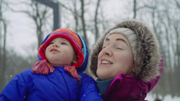 Alegre Madre Sosteniendo Hija Sonriendo Mirando Caer Nieve Invierno Vista — Vídeos de Stock