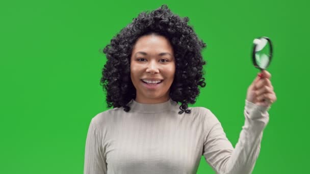 Afrikaans Amerikaanse Vrouw Glimlachen Kijkend Door Een Vergrootglas Geïsoleerd Groen — Stockvideo