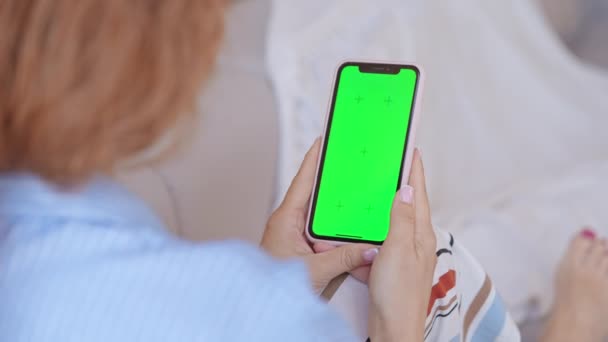 Woman Holding Smartphone Green Screen Indoors Sitting Sofa Wearing Blue — Stockvideo