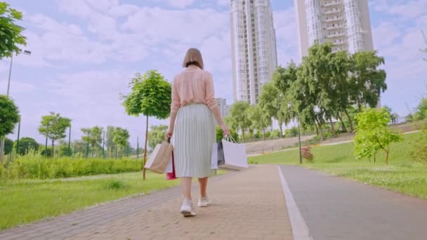 Ελκυστική Νεαρή Γυναίκα Κρατώντας Κιρσοί Χάρτινες Σακούλες Πόδια Στο Πάρκο — Αρχείο Βίντεο