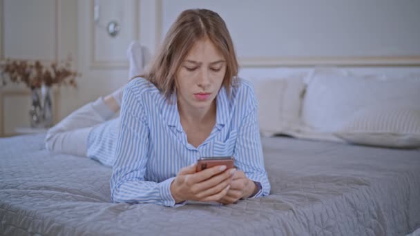 Annoyed Female Holding Mobile Reading Message Friend Lying Bed Bedroom — Vídeos de Stock
