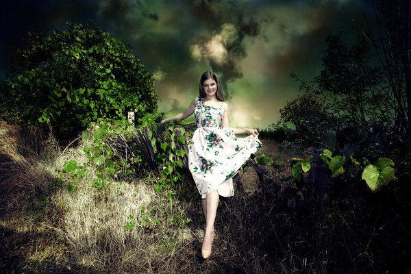 Smiling young woman fairy like in elegant dress in dark green environment