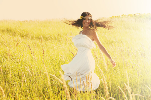 Happy smiling woman in boho style clothes run through the field, sunny summer day, retro colors