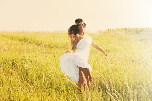 Happy smiling woman in boho style clothes run through the field, sunny summer day