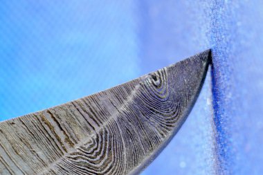 Birkaç katmanlı çelikten yapılmış elle dövülmüş bir bıçak. Stüdyoda özel bir desen çekilmiş.