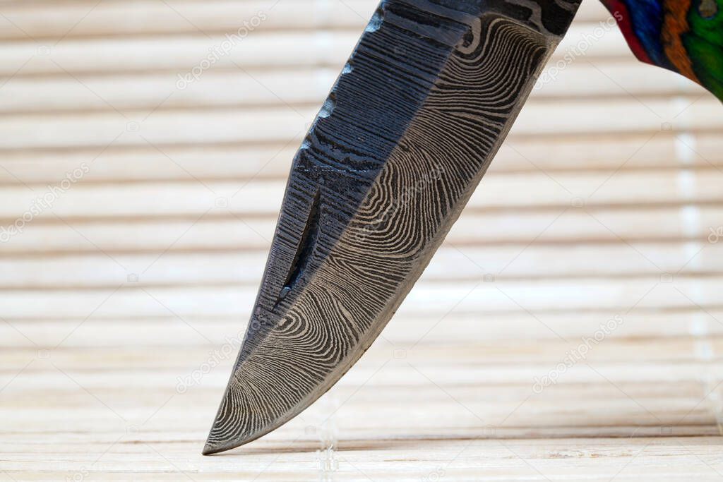 Hand-forged knife made of several layers of steel with an exclusive pattern photographed in the studio