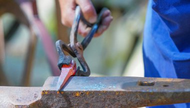 Demirci kızgın demirle çalışıyor.                             