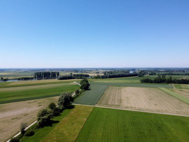 Hava aracı görüntüsü. Mavi gökyüzü ile yeşil arazi ve yol.
