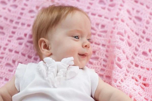 Das Baby liegt auf einem rosafarbenen Handtuch. sie trägt rosa Shorts und eine weiße Bluse. — Stockfoto