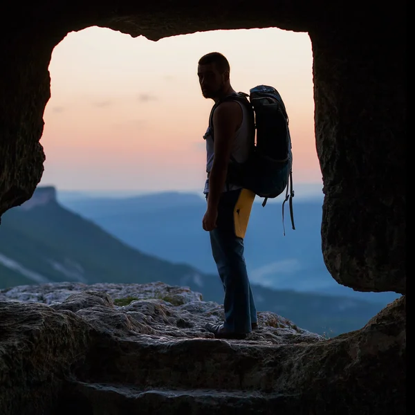 Silhouette of man with backpack in cave. — Stock Photo, Image