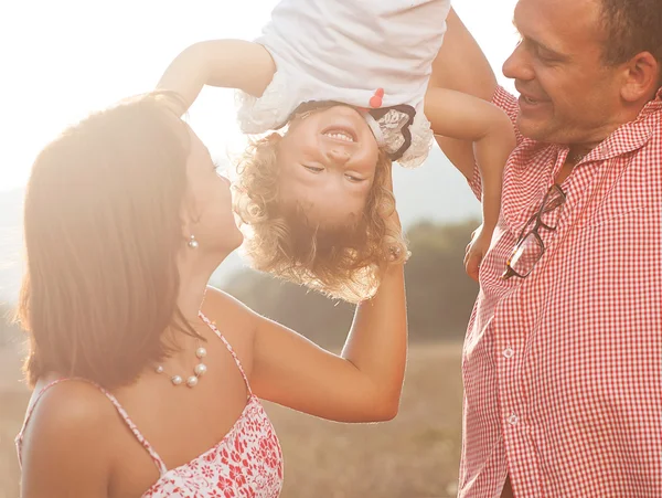 Happy mother and father kissing their daughter in the park — Stock Photo, Image