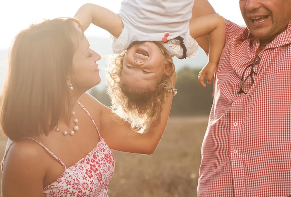 Happy mother and father kissing their daughter in the park — Stock Photo, Image