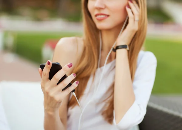 Young beautiful girl listening to mp3 player on the street in a cafe — Stock Photo, Image